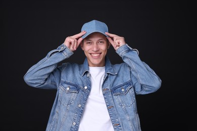 Photo of Young man wearing stylish denim baseball hat on black background