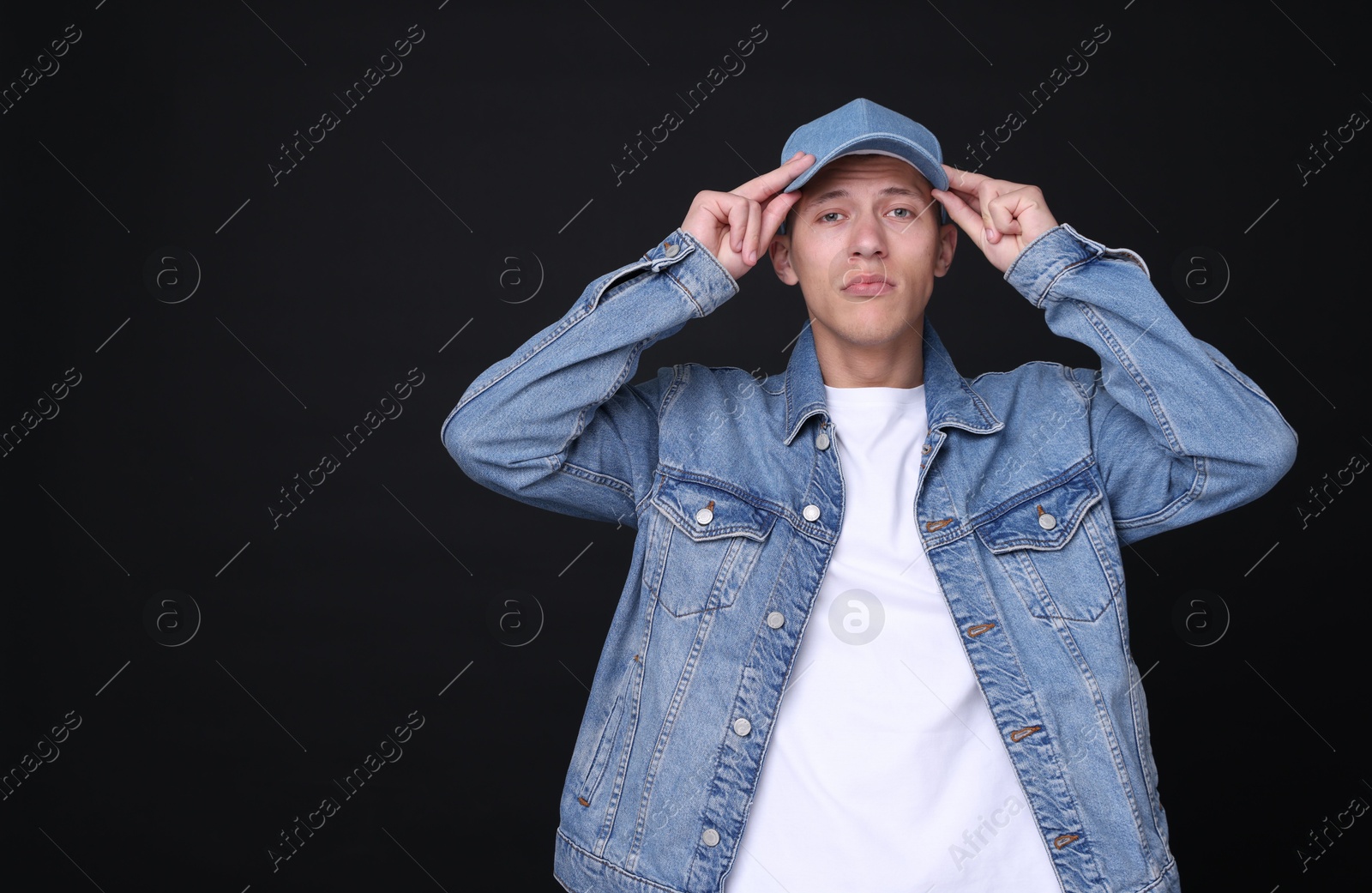Photo of Young man wearing stylish denim baseball hat on black background, space for text