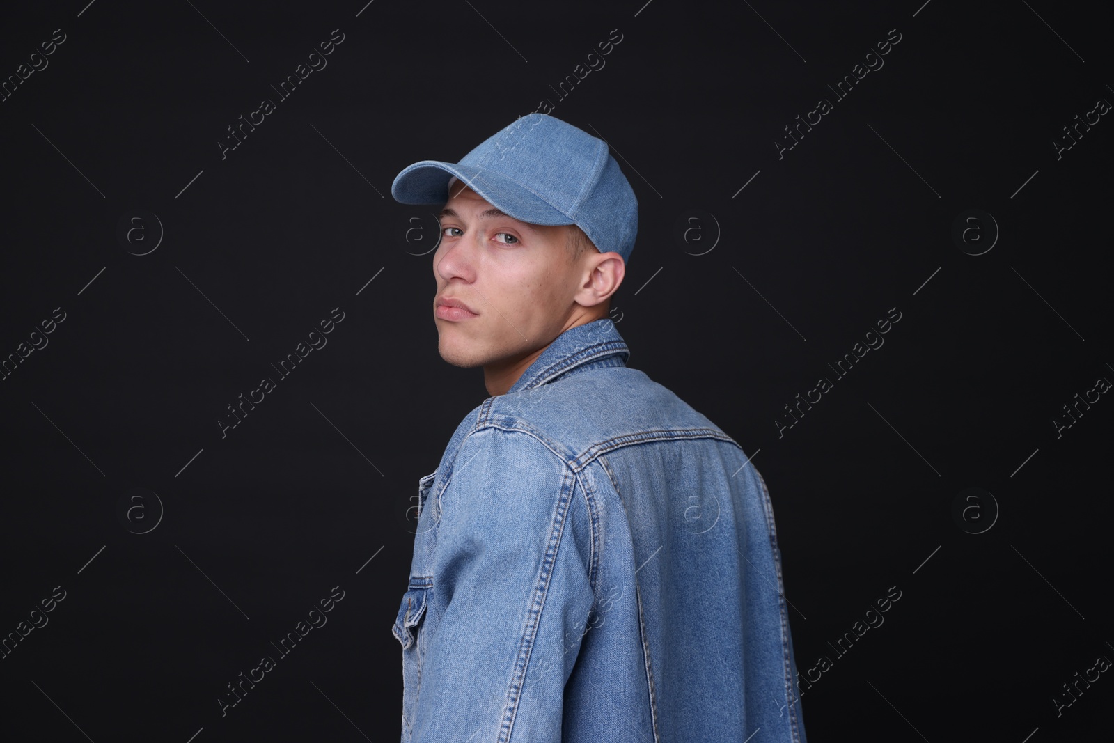 Photo of Young man wearing stylish denim baseball hat on black background