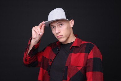 Photo of Young man wearing stylish baseball hat on black background