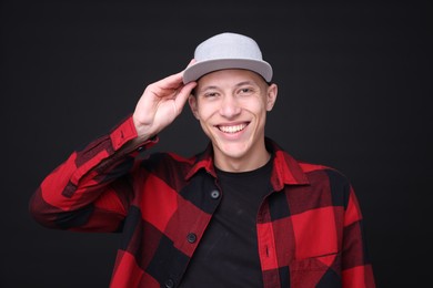 Photo of Young man wearing stylish baseball hat on black background
