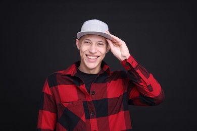 Photo of Young man wearing stylish baseball hat on black background
