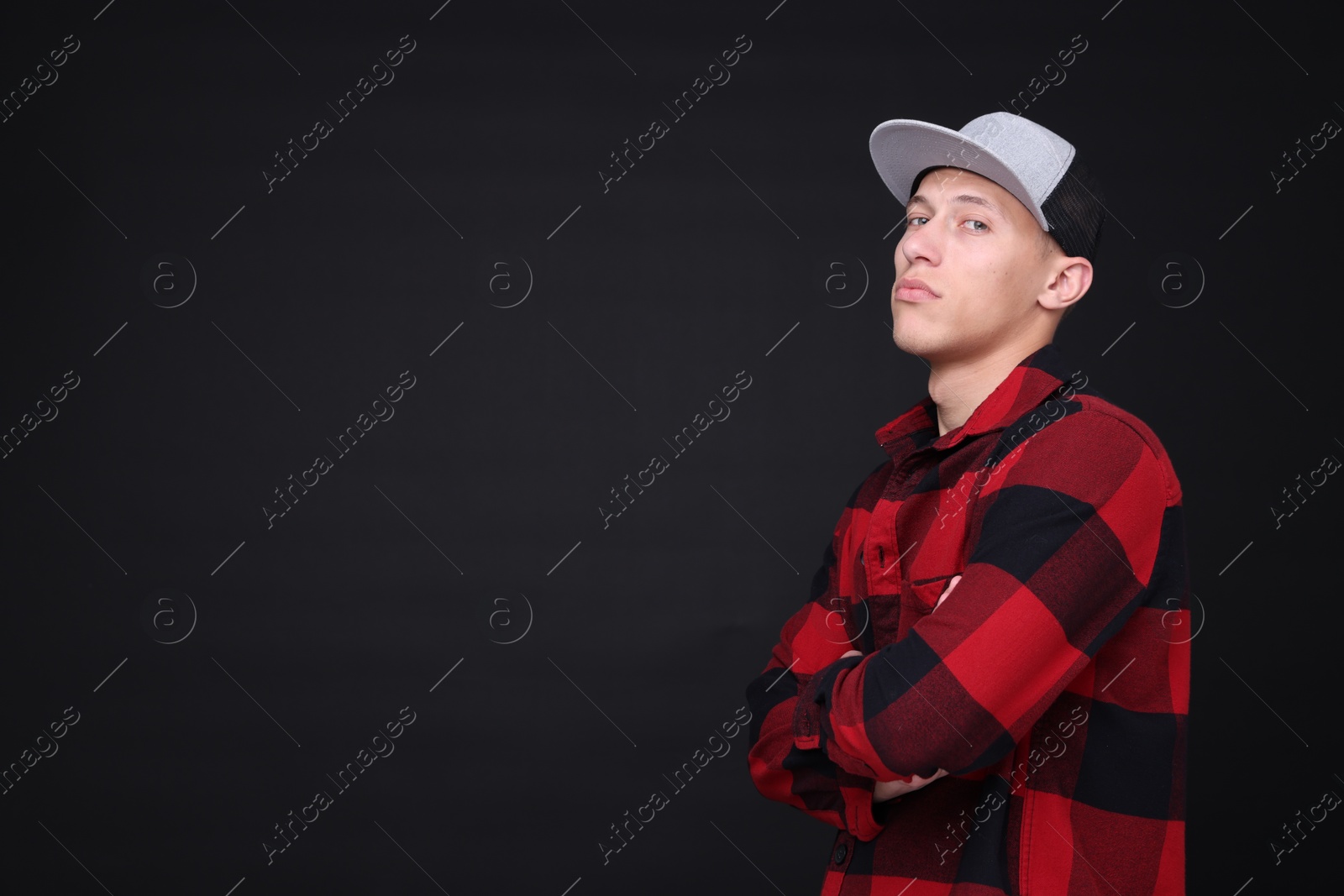 Photo of Young man wearing stylish baseball hat on black background, space for text