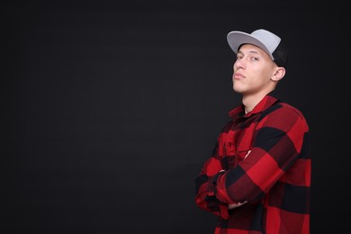 Photo of Young man wearing stylish baseball hat on black background, space for text