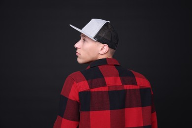 Photo of Young man wearing stylish baseball hat on black background