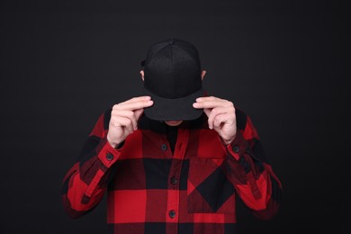 Photo of Young man wearing stylish baseball hat on black background