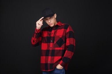 Photo of Young man wearing stylish baseball hat on black background