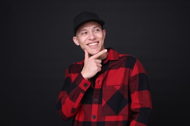 Photo of Young man wearing stylish baseball hat on black background