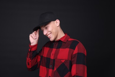 Photo of Young man wearing stylish baseball hat on black background