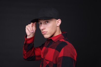 Photo of Young man wearing stylish baseball hat on black background