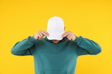 Photo of Young man wearing stylish white baseball hat on yellow background