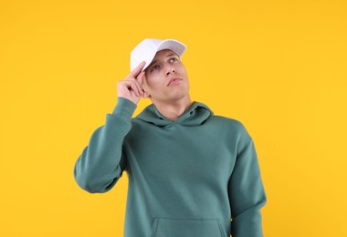 Photo of Young man wearing stylish white baseball hat on yellow background