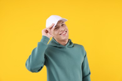 Photo of Young man wearing stylish white baseball hat on yellow background