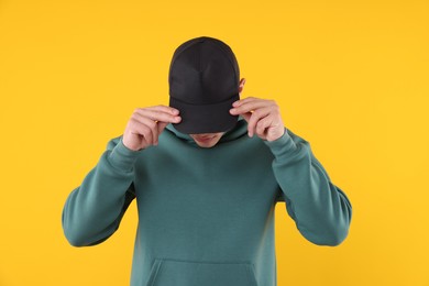 Photo of Young man wearing stylish black baseball hat on yellow background