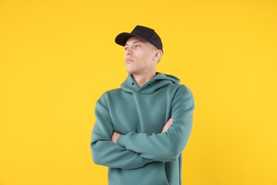 Photo of Young man wearing stylish black baseball hat on yellow background