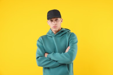 Photo of Young man wearing stylish black baseball hat on yellow background