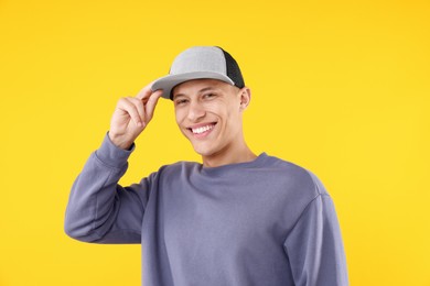 Photo of Young man wearing stylish baseball hat on yellow background