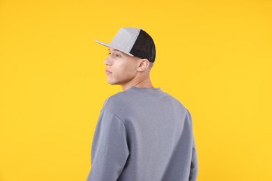 Photo of Young man wearing stylish baseball hat on yellow background