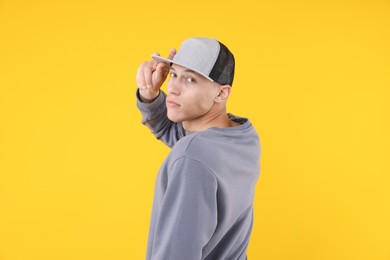 Photo of Young man wearing stylish baseball hat on yellow background
