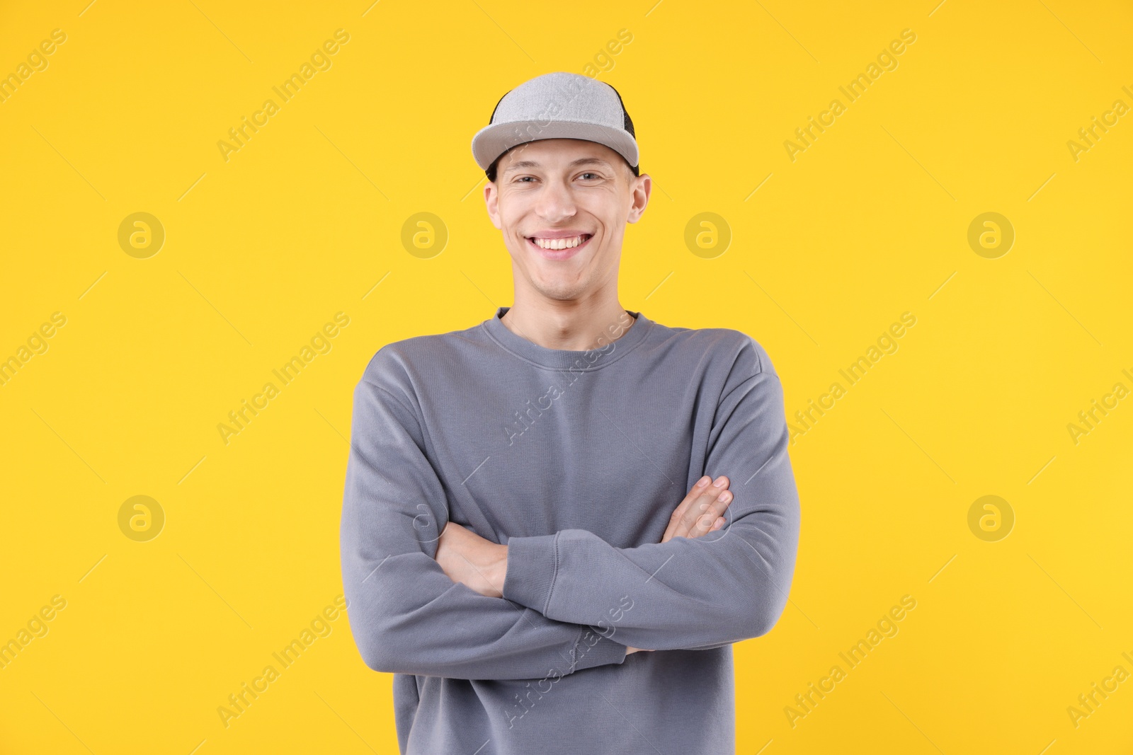 Young man wearing stylish baseball hat on yellow background Photo of Young man wearing stylish baseball hat on yellow background