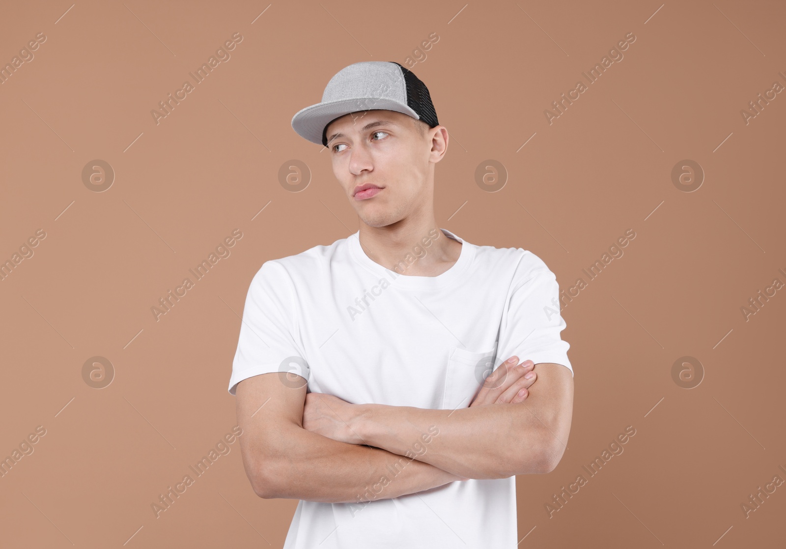 Young man wearing stylish baseball hat on light brown background Photo of Young man wearing stylish baseball hat on light brown background