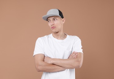 Photo of Young man wearing stylish baseball hat on light brown background