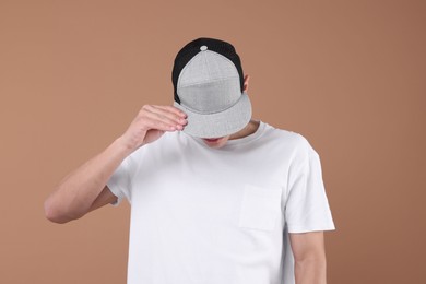 Photo of Young man wearing stylish baseball hat on light brown background
