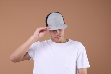 Photo of Young man wearing stylish baseball hat on light brown background