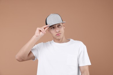 Photo of Young man wearing stylish baseball hat on light brown background