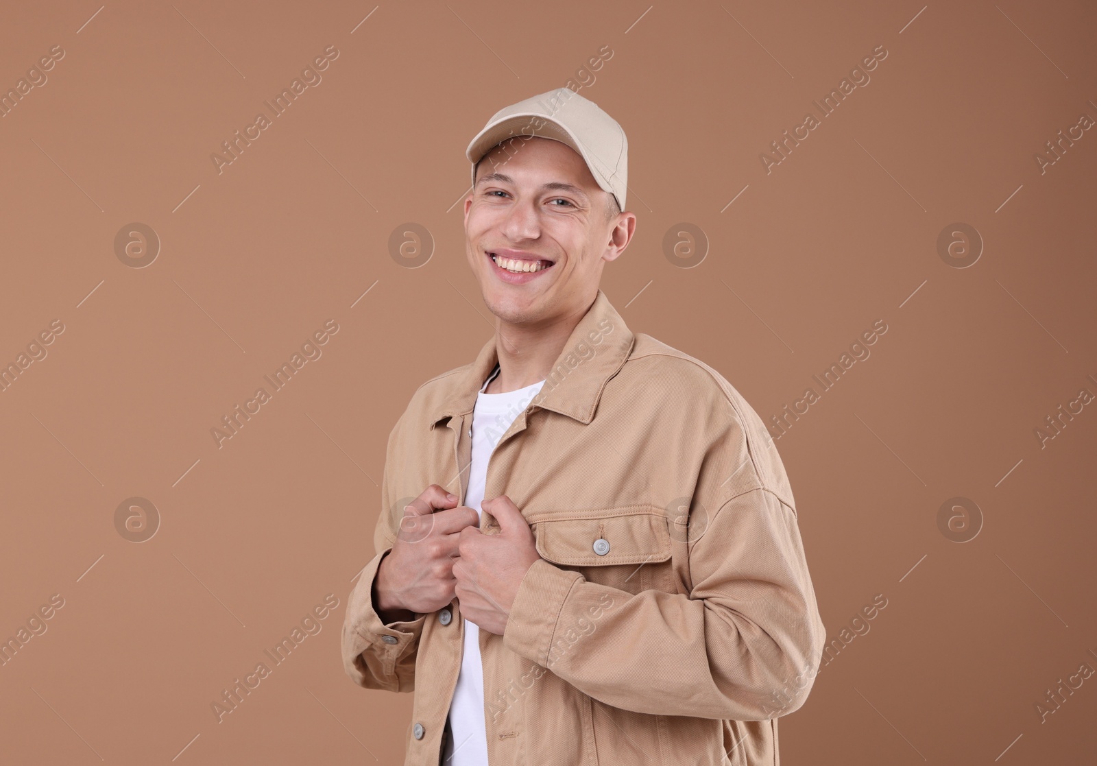 Young man wearing stylish beige baseball hat on light brown background Photo of Young man wearing stylish beige baseball hat on light brown background