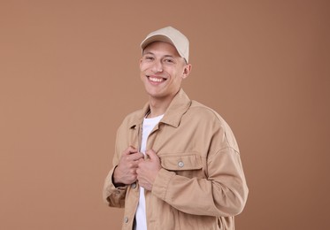Photo of Young man wearing stylish beige baseball hat on light brown background