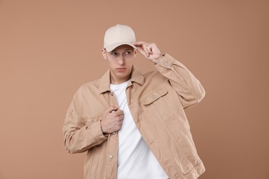 Photo of Young man wearing stylish beige baseball hat on light brown background