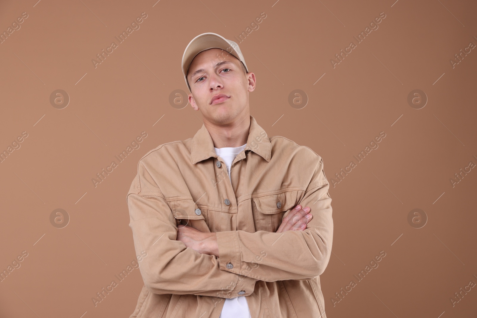 Young man wearing stylish beige baseball hat on light brown background Photo of Young man wearing stylish beige baseball hat on light brown background