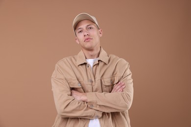 Photo of Young man wearing stylish beige baseball hat on light brown background