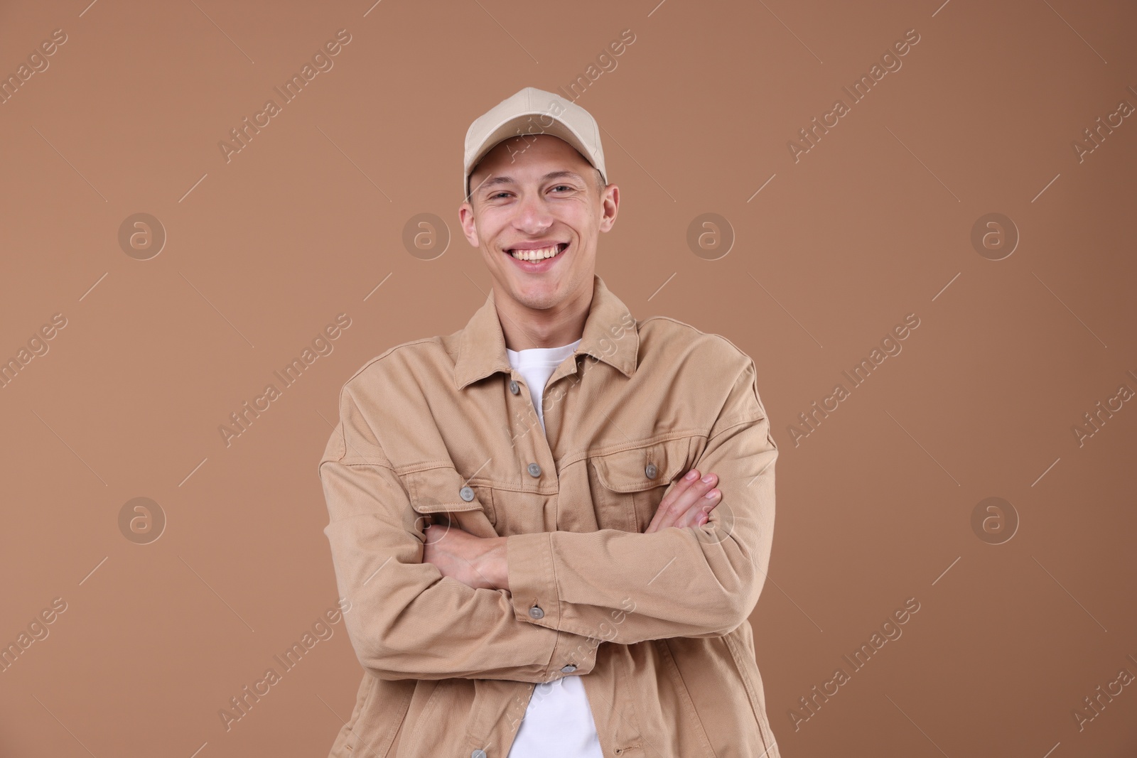 Young man wearing stylish beige baseball hat on light brown background Photo of Young man wearing stylish beige baseball hat on light brown background