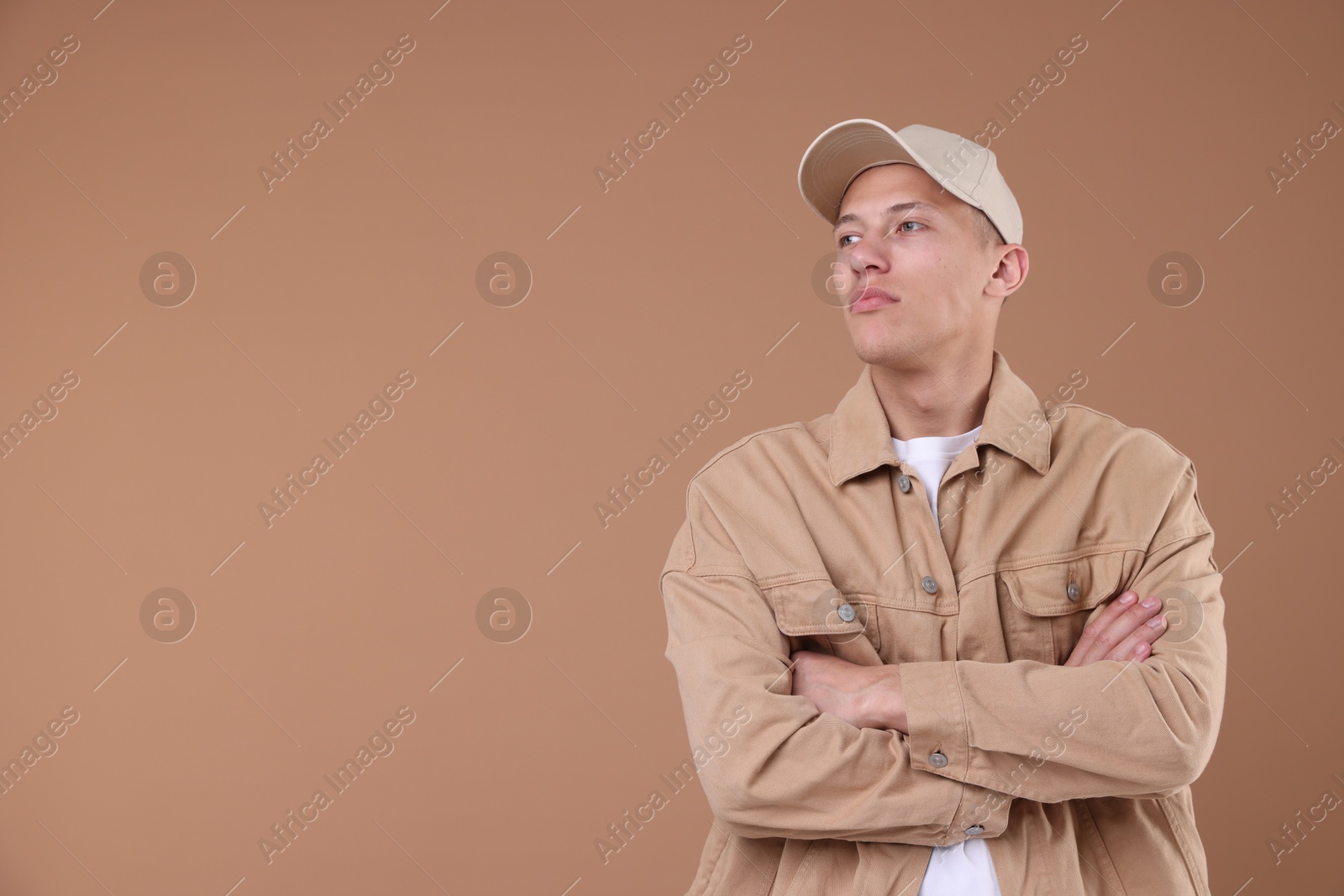 Young man wearing stylish beige baseball hat on light brown background, space for text Photo of Young man wearing stylish beige baseball hat on light brown background, space for text