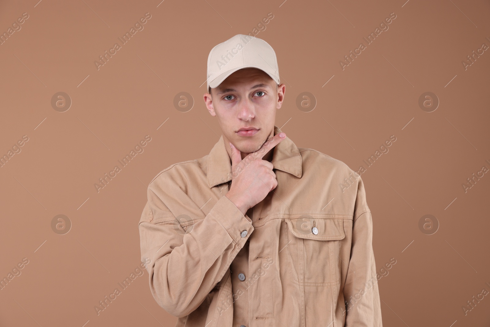 Young man wearing stylish beige baseball hat on light brown background Photo of Young man wearing stylish beige baseball hat on light brown background