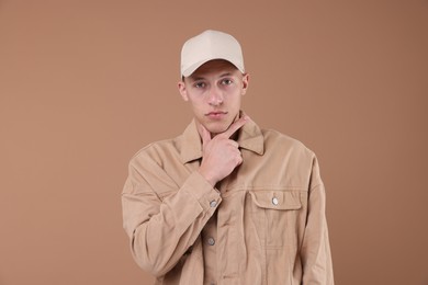 Photo of Young man wearing stylish beige baseball hat on light brown background