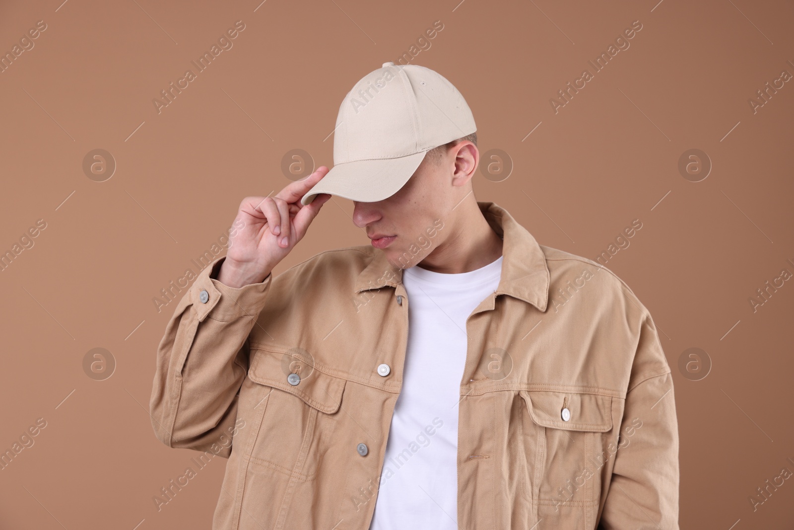 Young man wearing stylish beige baseball hat on light brown background Photo of Young man wearing stylish beige baseball hat on light brown background