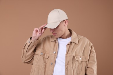 Photo of Young man wearing stylish beige baseball hat on light brown background