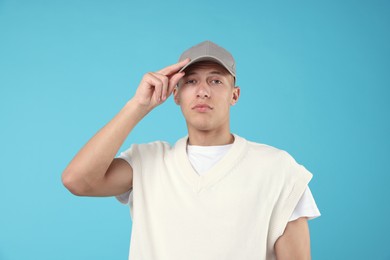 Photo of Young man wearing stylish grey baseball hat on light blue background
