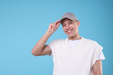 Photo of Young man wearing stylish grey baseball hat on light blue background, space for text