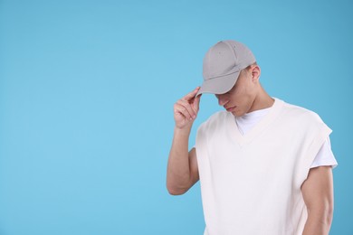 Photo of Young man wearing stylish grey baseball hat on light blue background, space for text