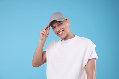 Photo of Young man wearing stylish grey baseball hat on light blue background