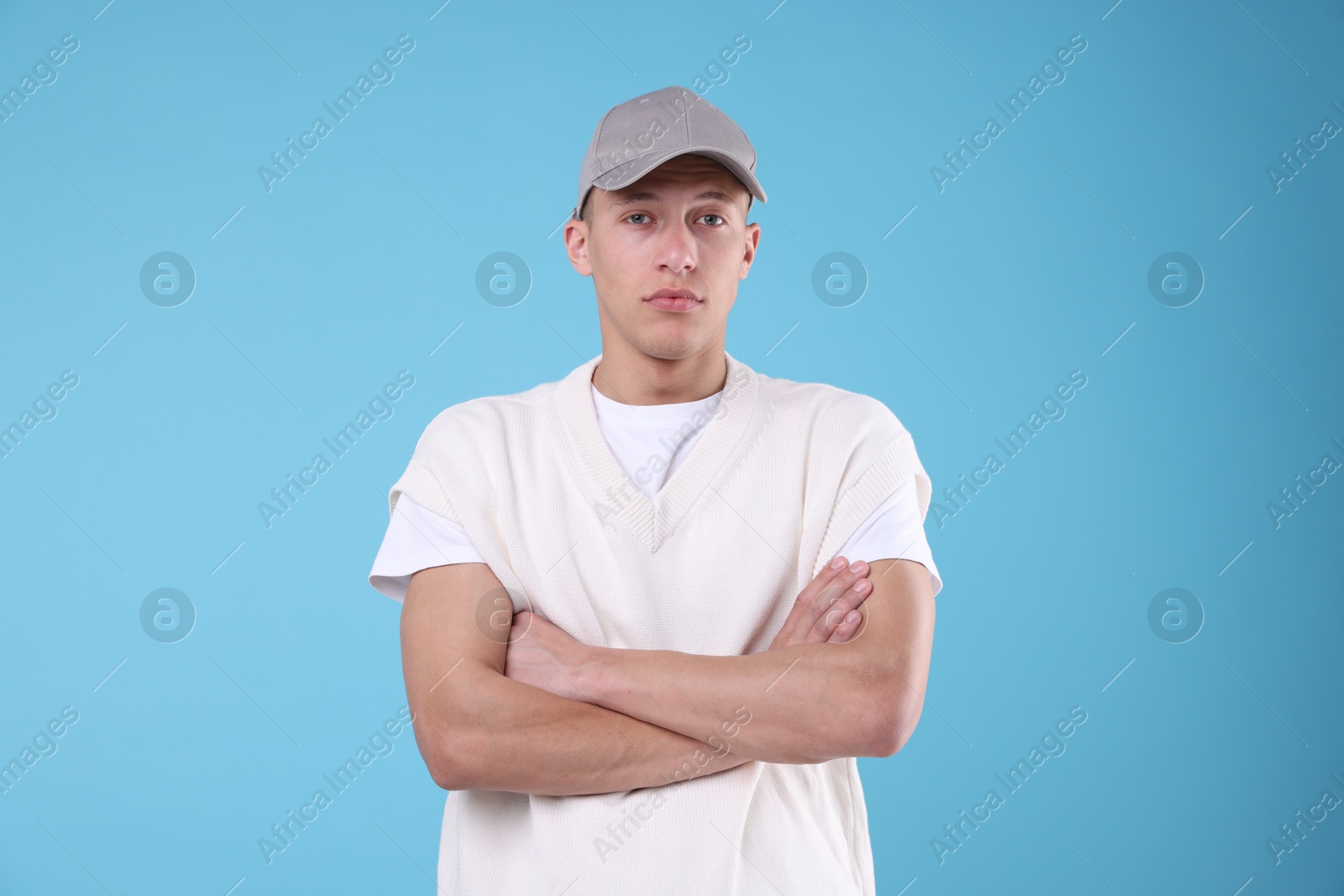 Young man wearing stylish grey baseball hat on light blue background Photo of Young man wearing stylish grey baseball hat on light blue background