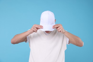 Photo of Young man wearing stylish white baseball hat on light blue background