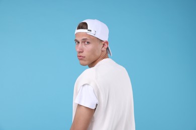 Photo of Young man wearing stylish white baseball hat on light blue background