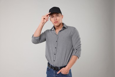 Photo of Young man wearing stylish black baseball hat on light grey background