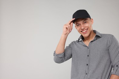 Photo of Young man wearing stylish black baseball hat on light grey background, space for text