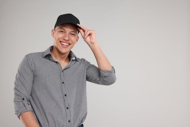 Photo of Young man wearing stylish black baseball hat on light grey background, space for text